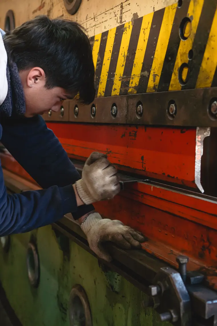 Worker adjusting a sheet in the press brake