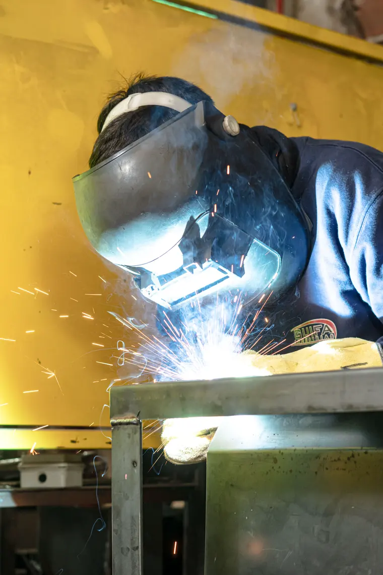 Welding a hopper in front of the yellow press brake